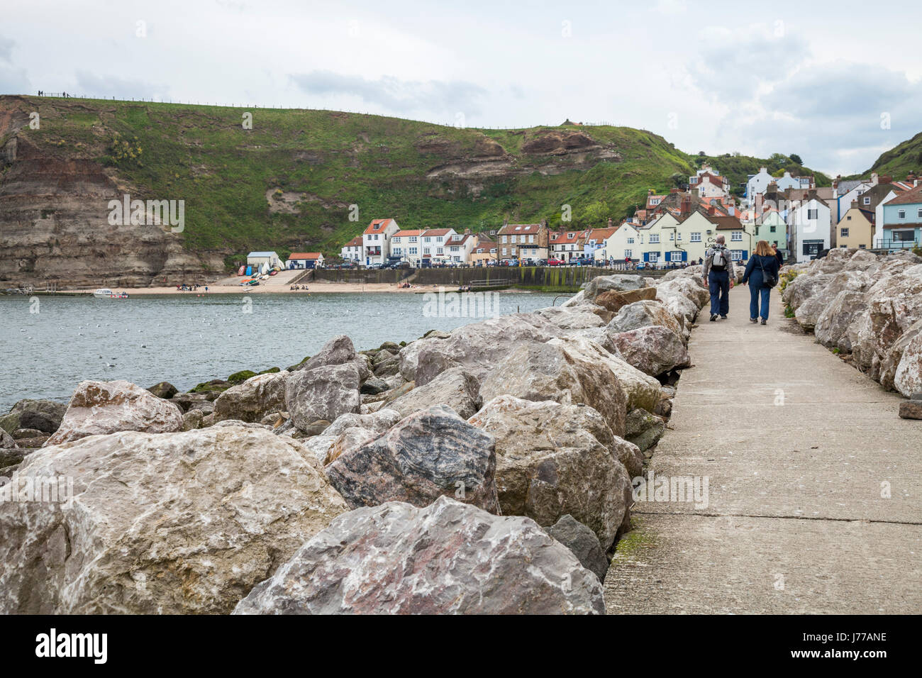 Un couple marche le long du chemin menant à la mer à Staithes, North Yorkshire, Angleterre, Royaume-Uni Banque D'Images