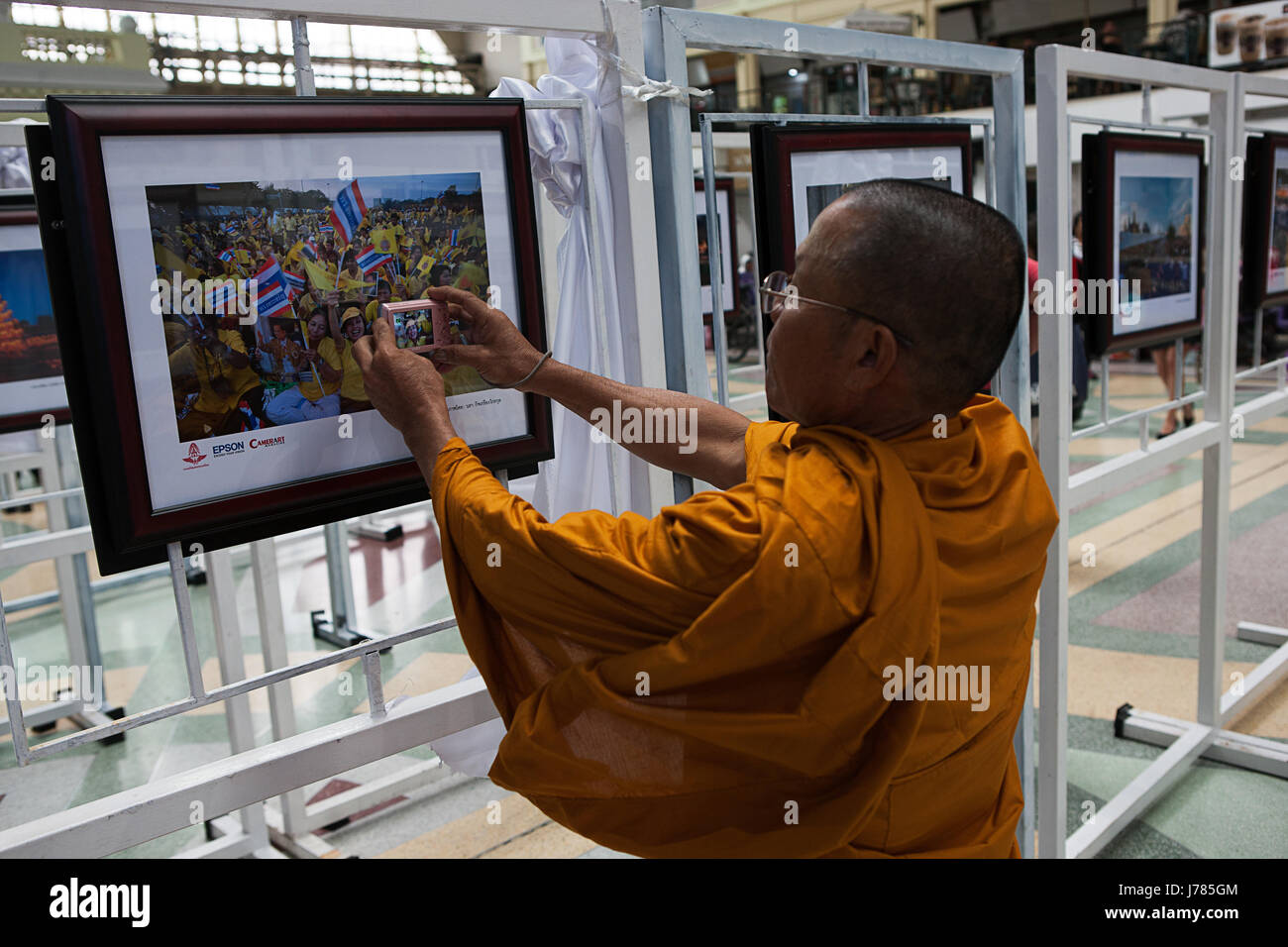 Un affichage de photos d'événements passés en hommage au Roi Bhumibol Adulyadej de Thaïlande. Un moine évoque l'image dans une photo. Banque D'Images