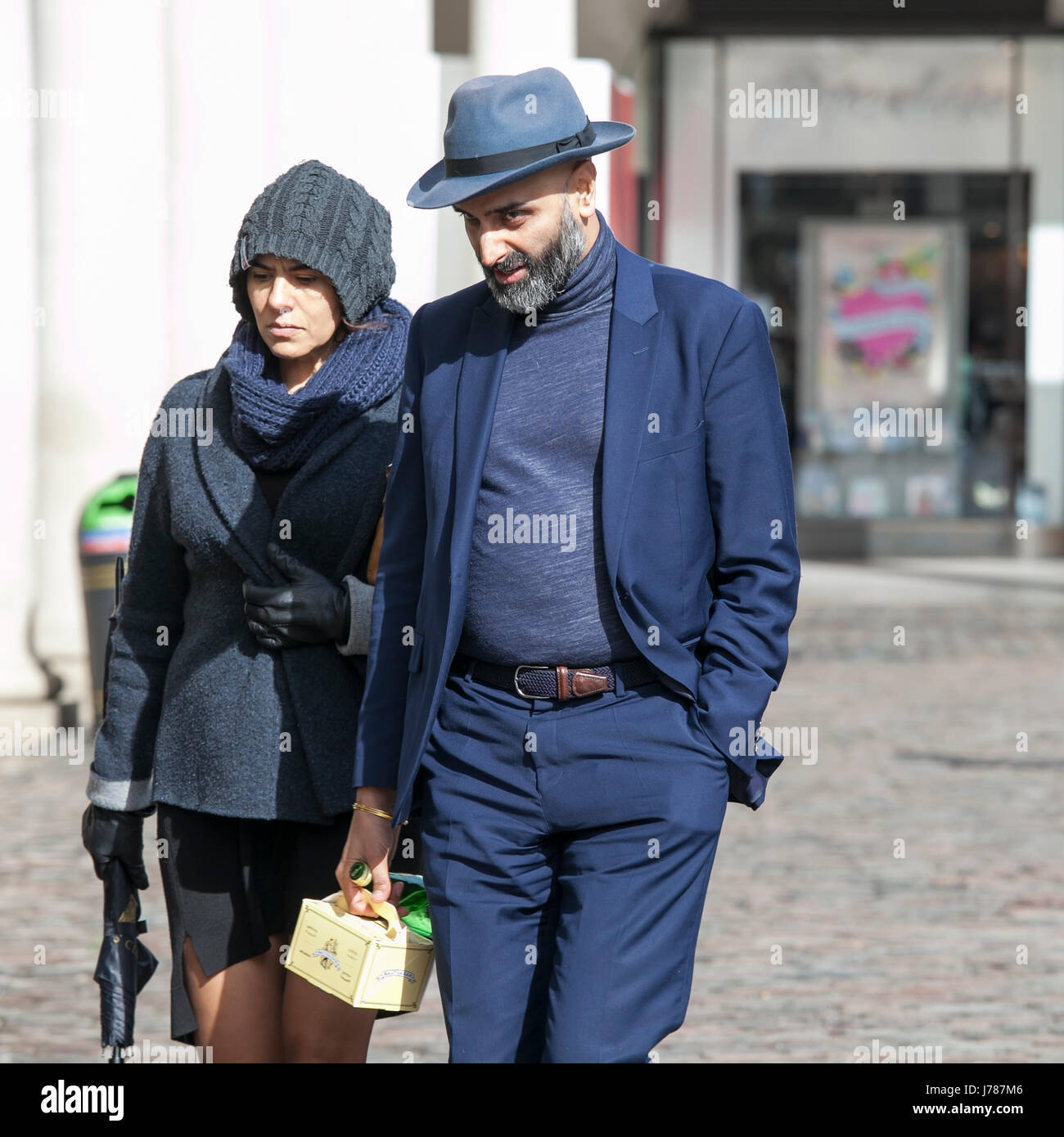 Londres, ANGLETERRE - Mars 12, 2017 à un homme et de la femme de costumes bleus et de chapeaux de marcher dans les rues de Covent Garden. Banque D'Images