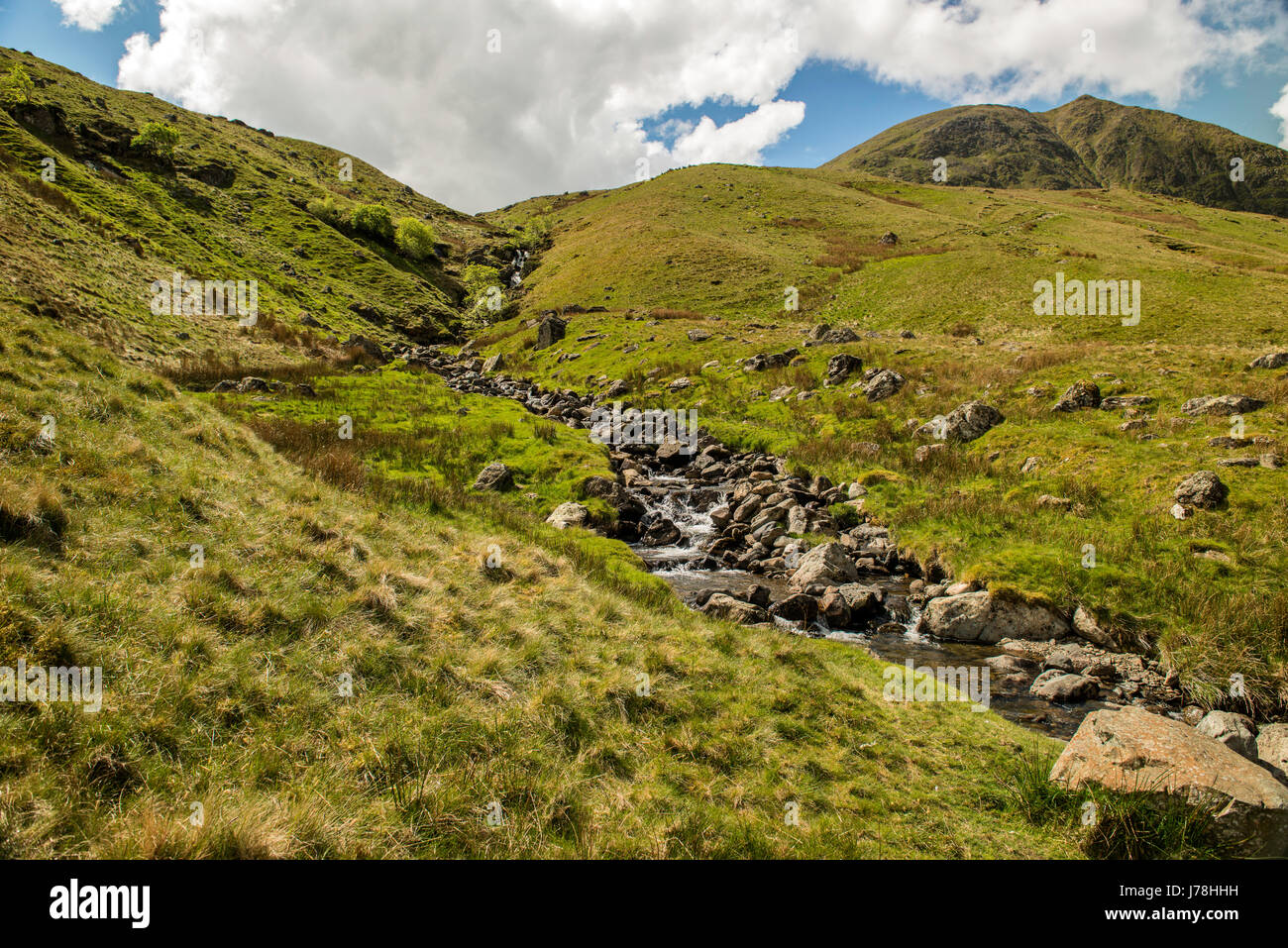 Le paysage de Cumbria et eaux en cascade Falls de Red Tarn Beck avec Helvellyn et Swirral Edge dans l'arrière-plan sur un ciel bleu. Banque D'Images