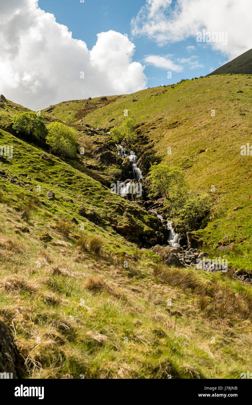 Le paysage de Cumbria et eaux en cascade Falls de Red Tarn Beck avec Helvellyn et Swirral Edge dans l'arrière-plan sur un ciel bleu. Banque D'Images