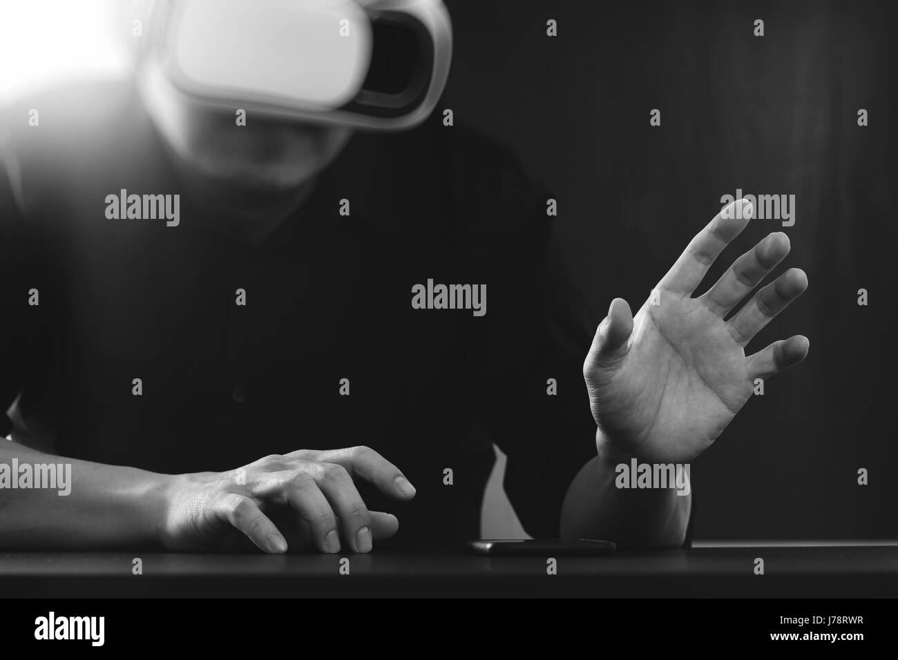 Businessman wearing lunettes de réalité virtuelle dans un bureau moderne avec l'aide du Smartphone avec casque VR noir et blanc Banque D'Images