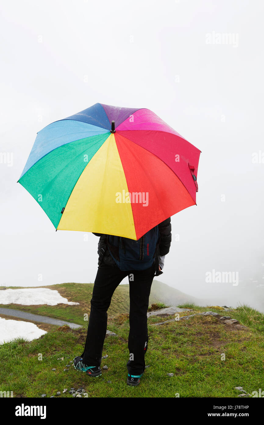 Une femme donne au paysage de montagne tenant un parapluie de golf aux couleurs vives, elle se dresse sur la première montagne dans la région de Jungfrau de Suisse. Banque D'Images