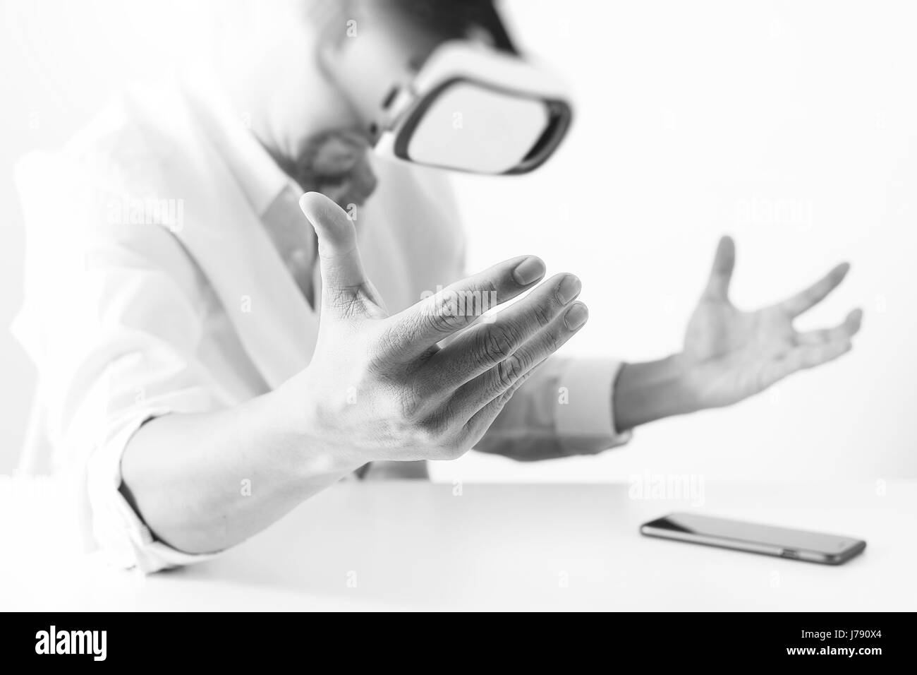 Businessman wearing lunettes de réalité virtuelle dans un bureau moderne avec l'aide du Smartphone avec casque VR noir et blanc Banque D'Images