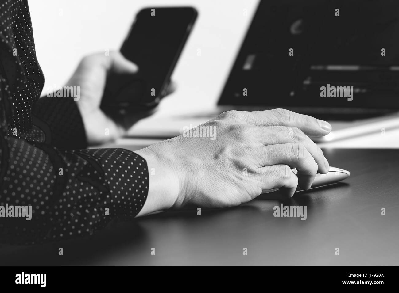 Close up of businessman part travailler avec smart phone et l'ordinateur portable et tablette numérique dans l'ordinateur de bureau moderne, noir et blanc Banque D'Images