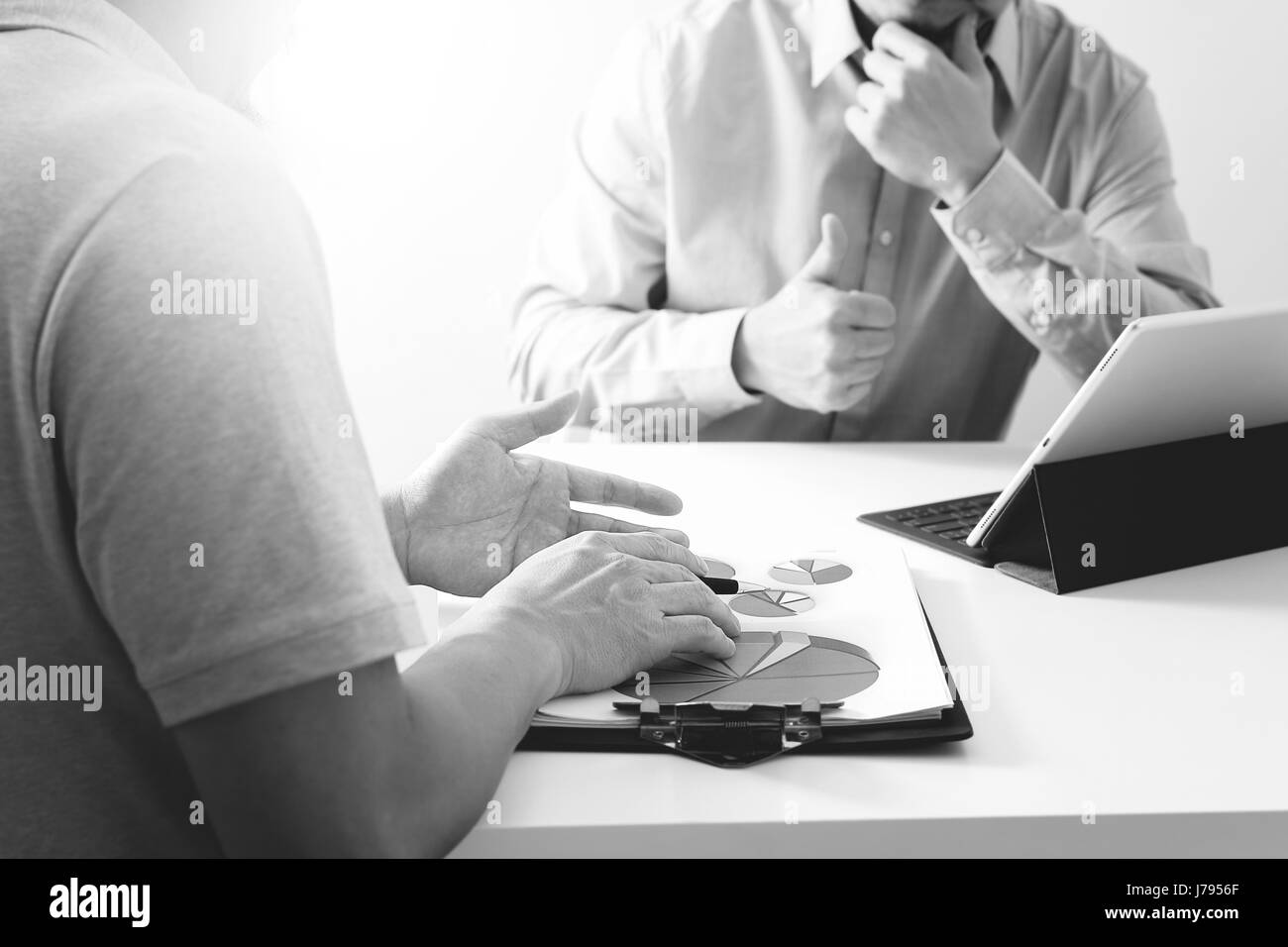 Les hommes d'affaires de travailler ensemble sur un document et à l'aide de smart phone et tablette numérique et votre ordinateur de bureau moderne en noir et blanc, Banque D'Images