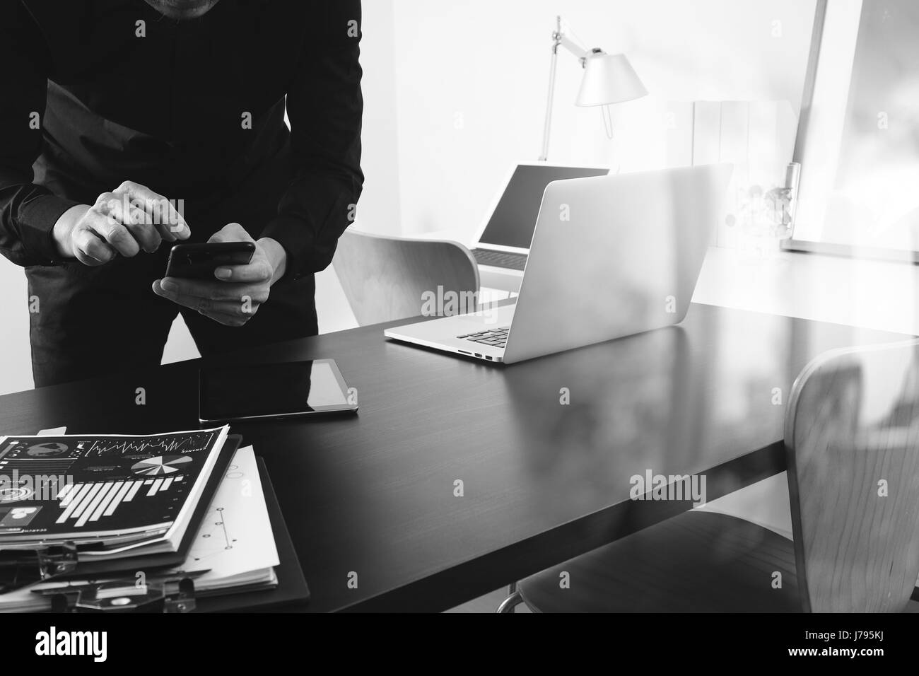 Businessman ou le concepteur à l'aide de smart phone avec latop et digital tablet computer et document sur 24 dans un bureau moderne, noir et blanc Banque D'Images