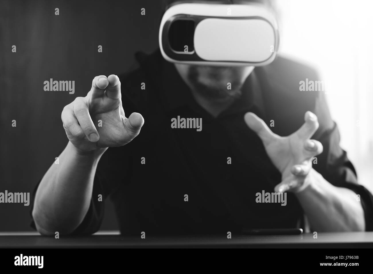 Businessman wearing lunettes de réalité virtuelle dans un bureau moderne avec l'aide du Smartphone avec casque VR noir et blanc Banque D'Images