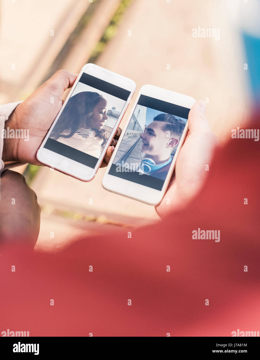 Mains tenant des téléphones intelligents avec des photos d'un jeune couple Banque D'Images