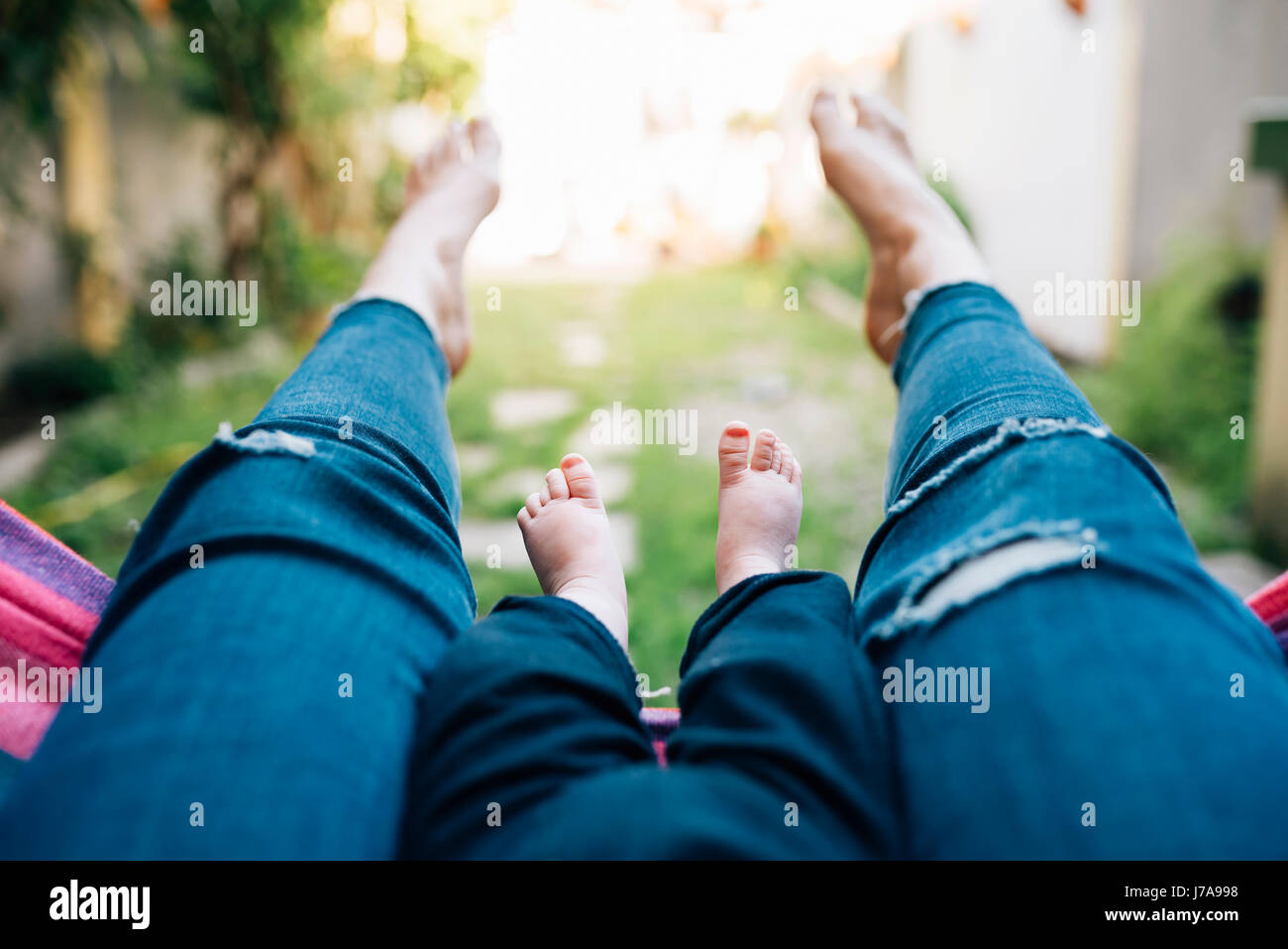 Mère et bébé girl lying pieds nus sur un hamac, vue partielle Banque D'Images