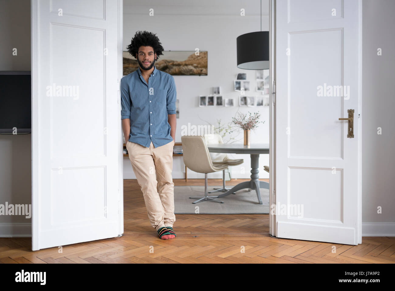 L'homme à la maison debout dans le cadre de la porte dans la salle de séjour Banque D'Images L'homme à la maison debout dans le cadre de la porte dans la salle de séjour Banque D'Images