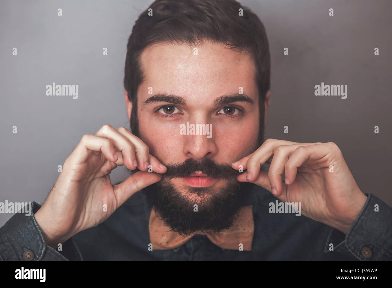 Homme barbu portant des moustaches, ajustant sa chemise en jean et le liège Bow Tie Banque D'Images