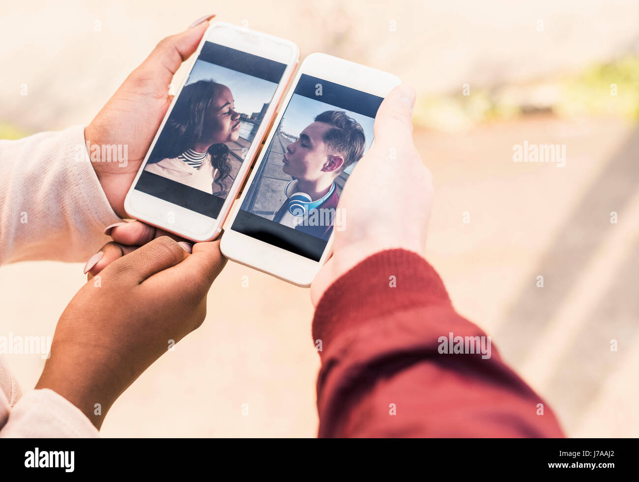 Mains tenant des téléphones intelligents avec des photos d'un jeune couple Banque D'Images