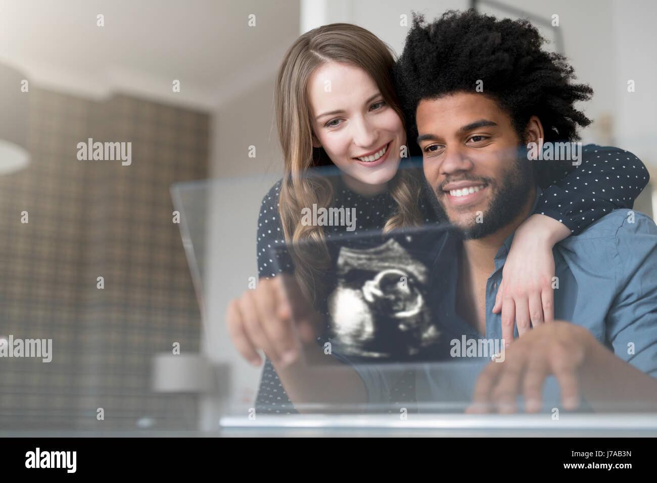 Smiling couple looking at ultra sound photo de bébé sur l'écran futuriste Banque D'Images