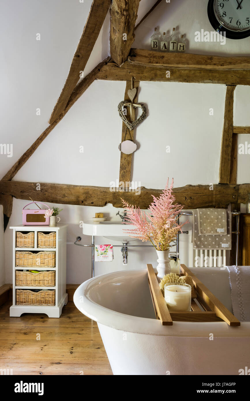 Salle de bains voûtée ancienne avec poutres apparentes, mur en briques apparentes et roll-top de bain français. Banque D'Images