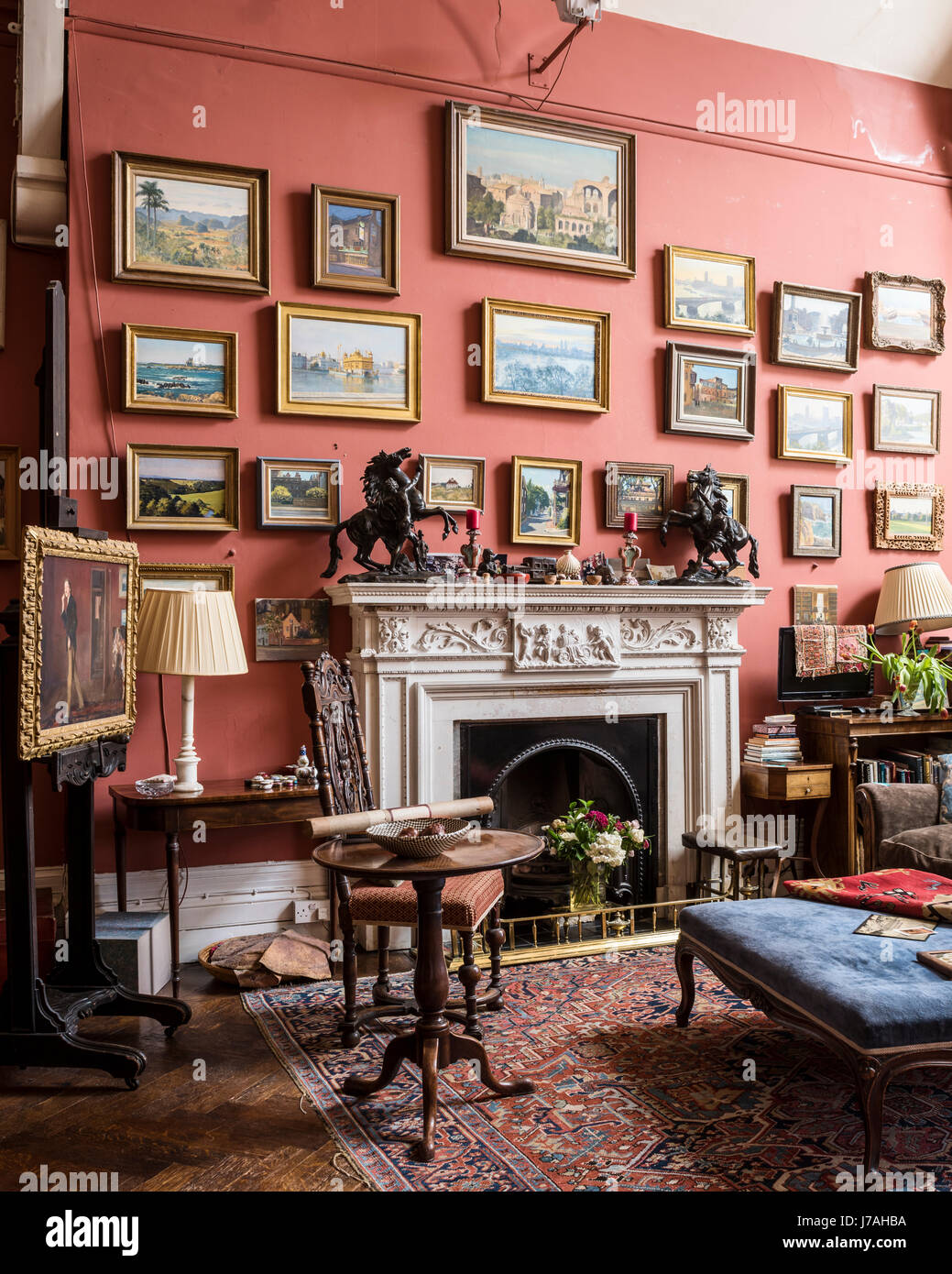 Une collection de peintures à Julian Barrow au-dessus d'une cheminée avec récupération de velours bleu pouf. Les murs sont peints dans l'ouvrage de Farrow & Ball Prix Re Banque D'Images