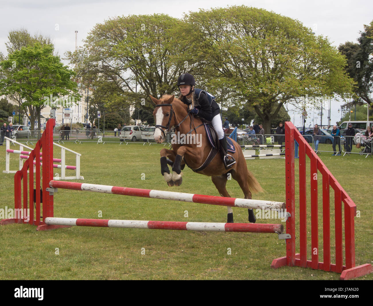 Un adolescent à cheval prend un saut lors d'un concours de saut. Banque D'Images