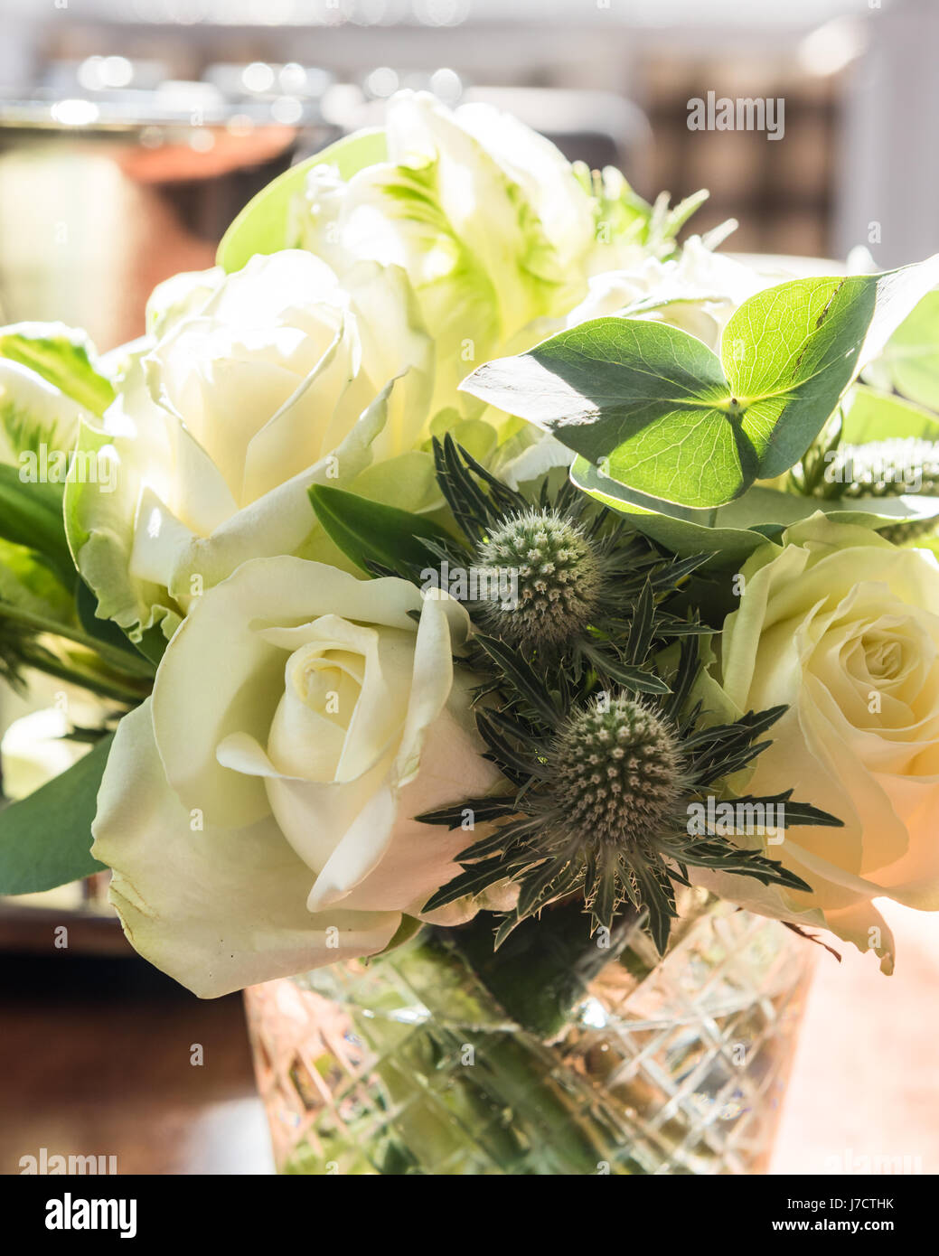 Un posey de roses blanches et de chardons en vase en verre Banque D'Images