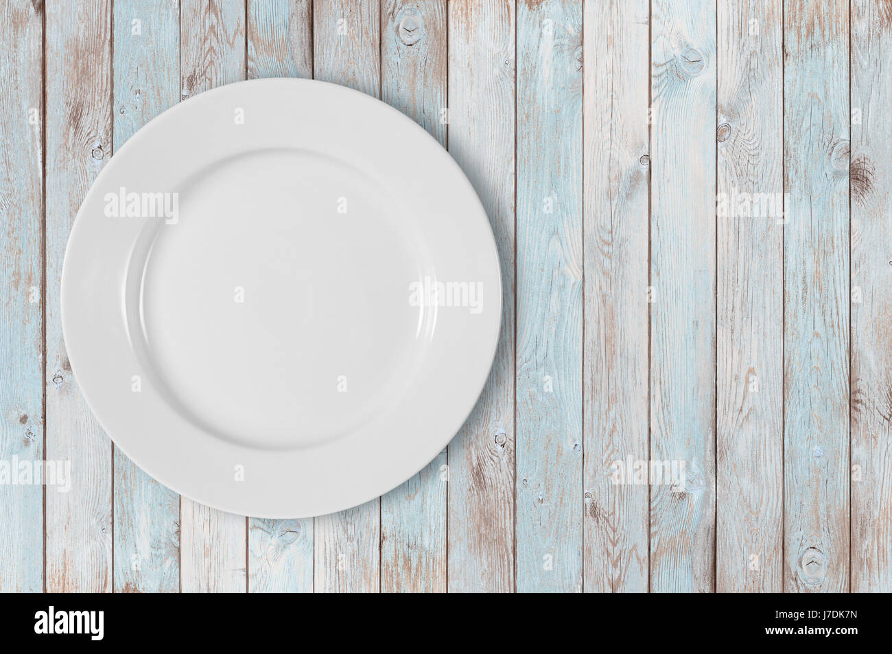 Assiette vide blanc sur le côté gauche du tableau en bois bleu Banque D'Images