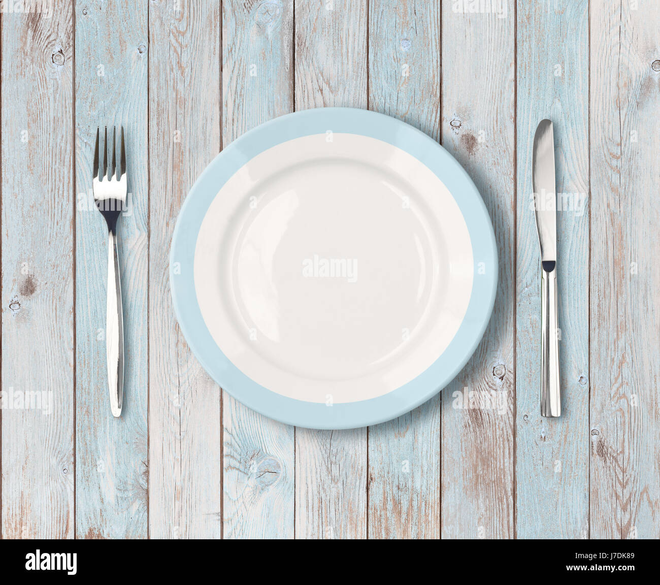 Assiette vide blanc avec bordure bleue sur table en bois Banque D'Images