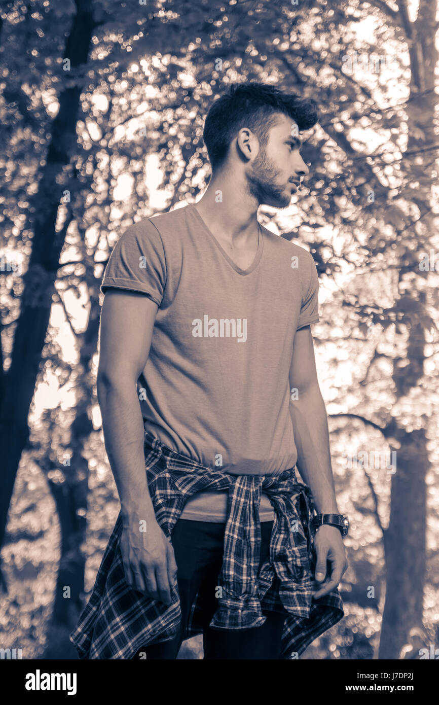 Un jeune homme adultes uniquement, à l'écart, parc nature dehors les arbres, image en noir et blanc Banque D'Images
