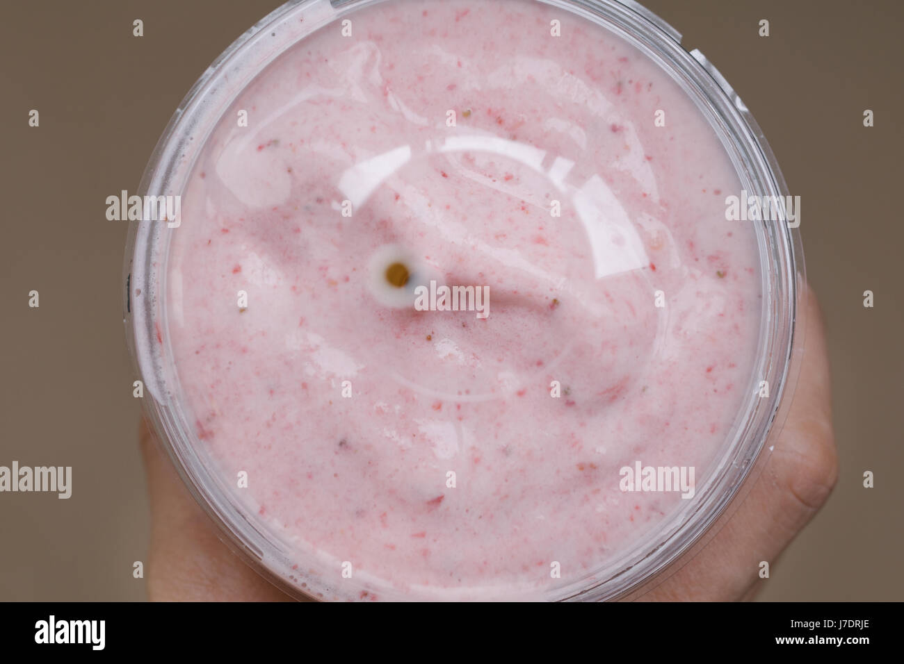 Main tenant un smoothie aux fraises dans une tasse en plastique avec une paille . Concept de vie sain. Banque D'Images