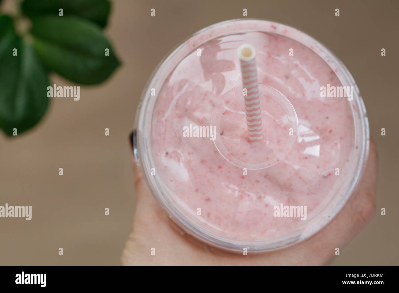 Main tenant un smoothie aux fraises dans un godet en plastique avec une paille. L'été et de vie sain concept. Banque D'Images