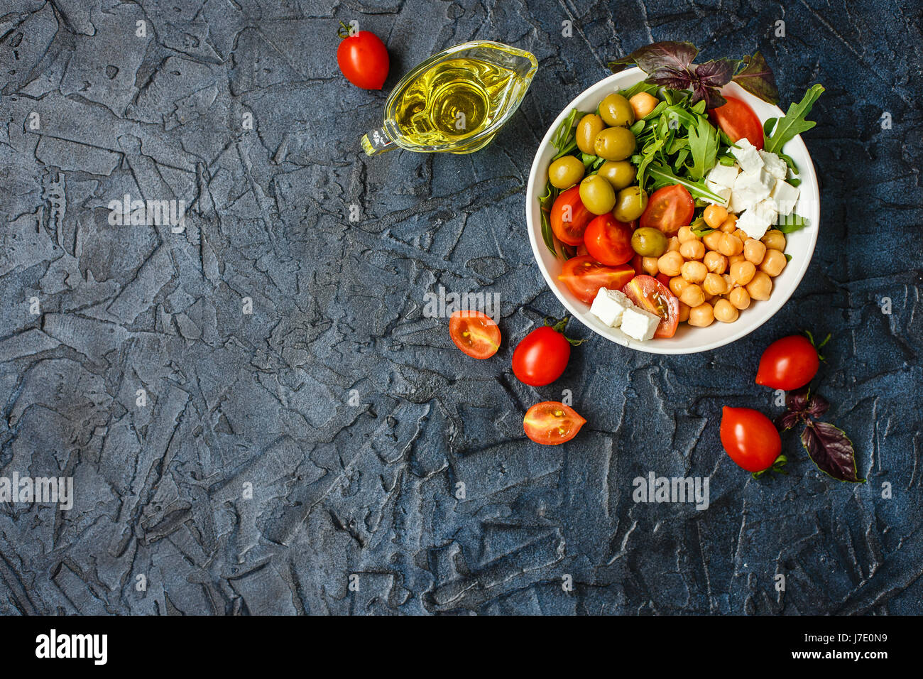Bol de Bouddha végétarien avec les pois chiches, la roquette, tomates cerises, fromage feta et olives. L'huile d'olive, les tomates sur la table, alimentation saine. Vue d'en haut. P Banque D'Images