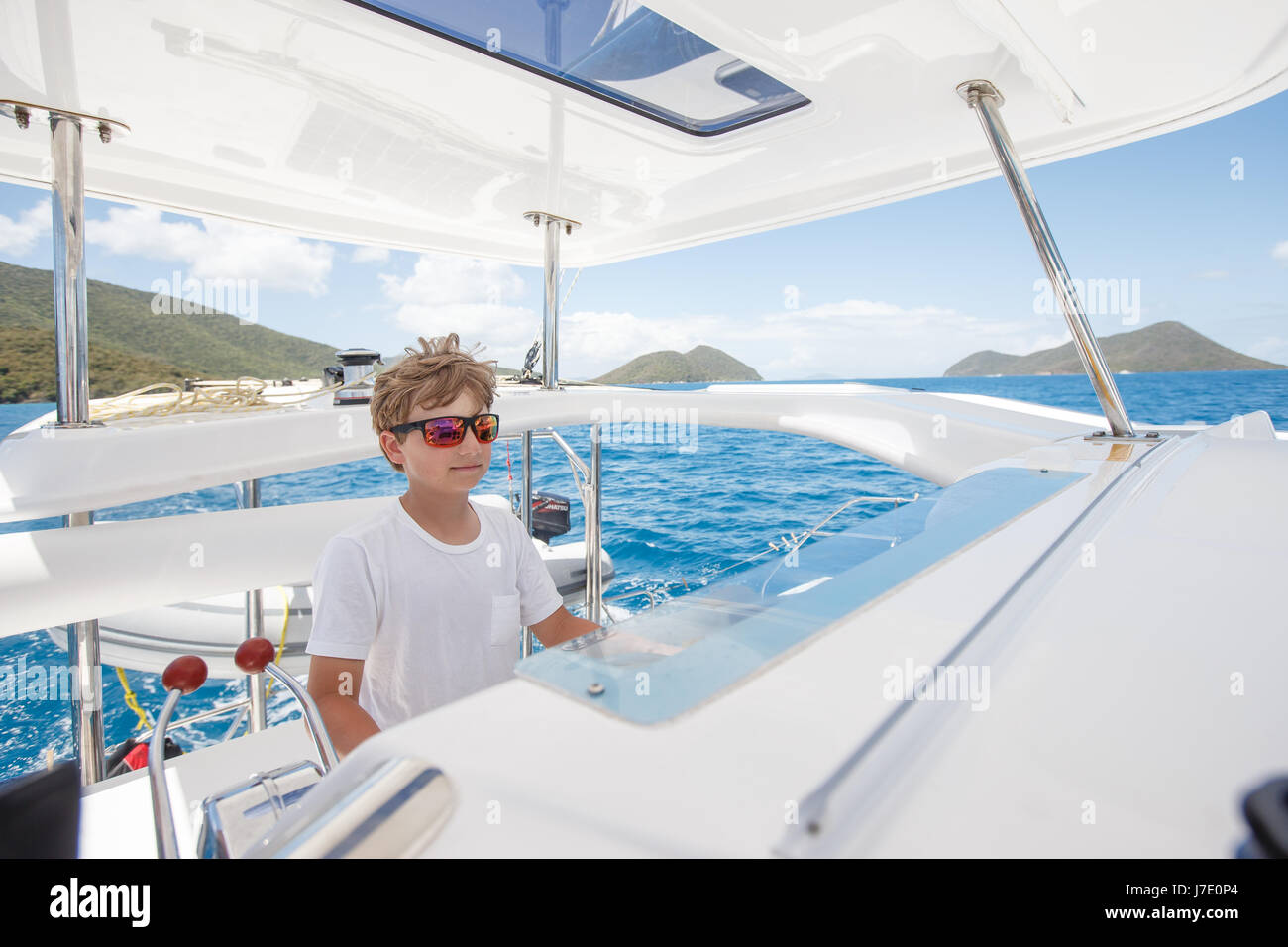 Jeune marin garçon prend la barre et voiles grand voile seul / solo en Caraïbes Banque D'Images