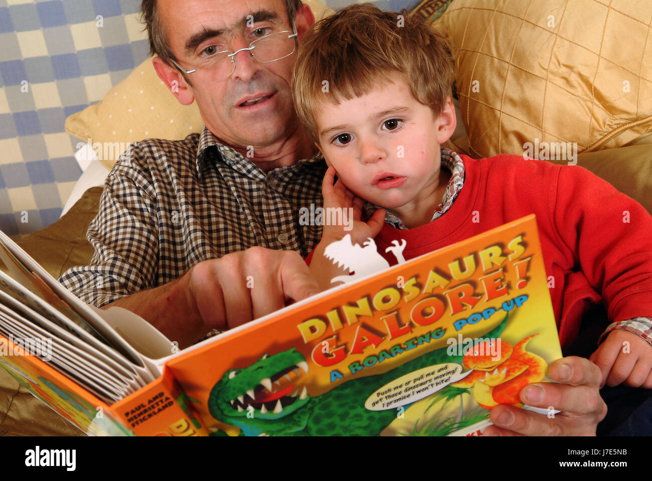 Paul Stickland la lecture au lit avec les enfants Arthur (3) en rouge et Felix (11) Banque D'Images