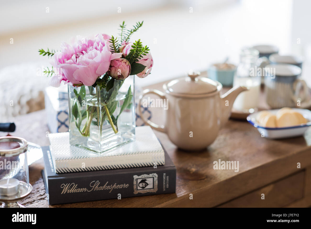 Vase carré en verre rose avec pivoines sur table basse Banque D'Images