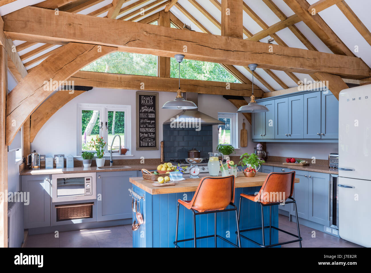 L'unité de l'île lumineuse peinte en bleu par Stiffkey Farrow & Ball en chêne avec cuisine à pans suspendus Banque D'Images