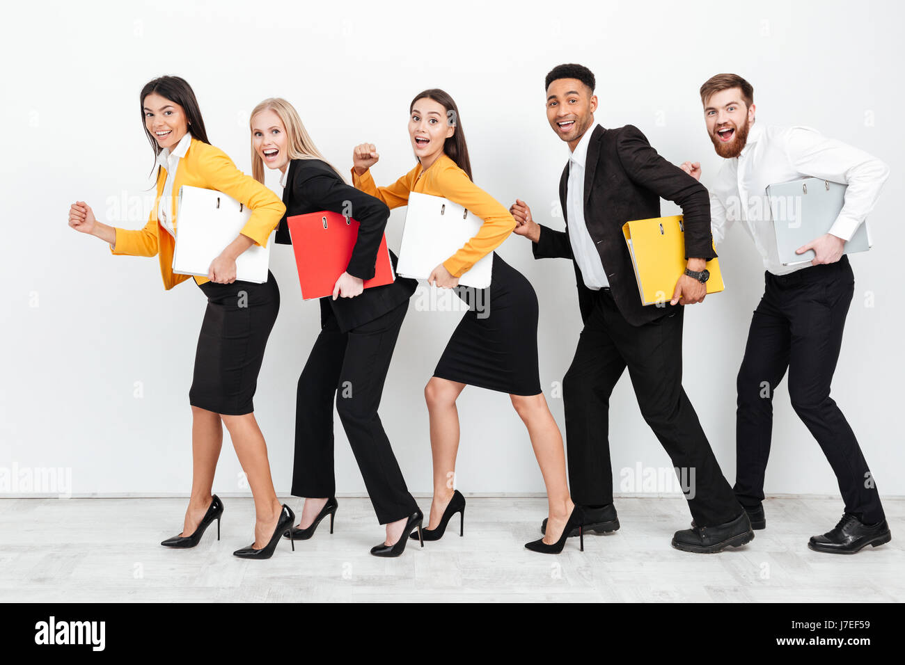 Photo d'un groupe de collègues heureux isolé marche avec folders in office. En regardant la caméra. Banque D'Images