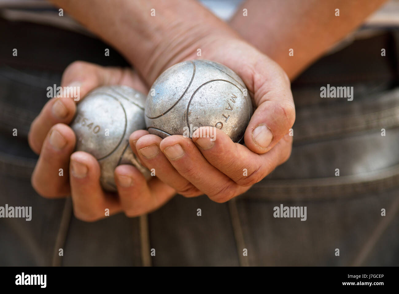 Male hands holding Pétanque boules, Sanary-sur-Mer, Var, France Banque D'Images