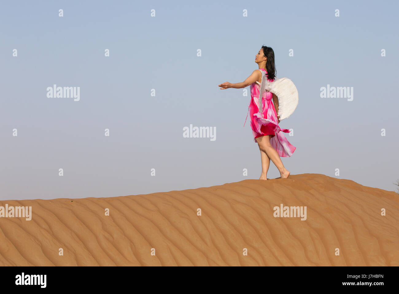 Jeune femme avec des ailes d'angle dans un désert Banque D'Images