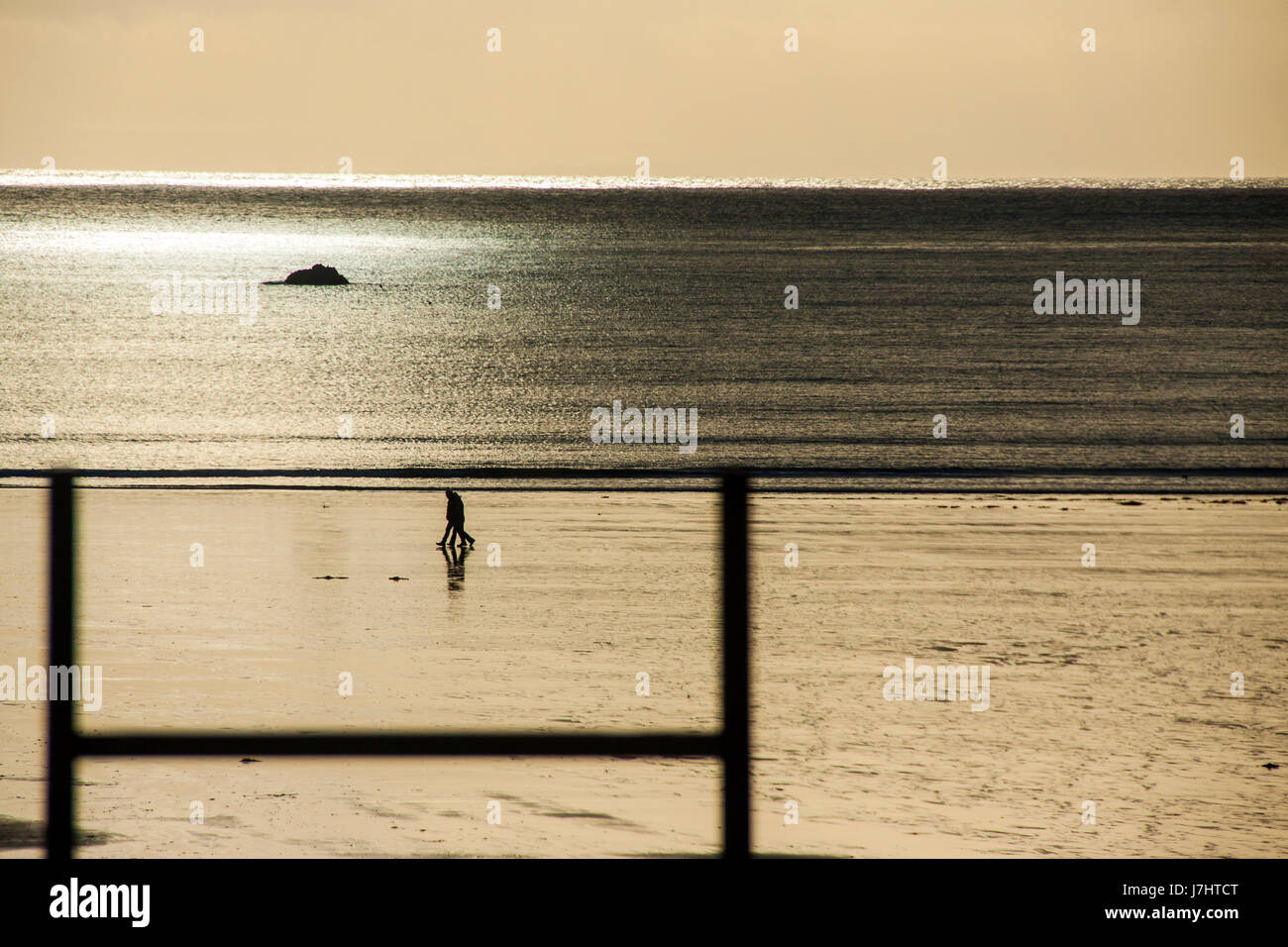 Un couple marche sur la plage à St Brelade, Jersey, Channel Islands. Banque D'Images