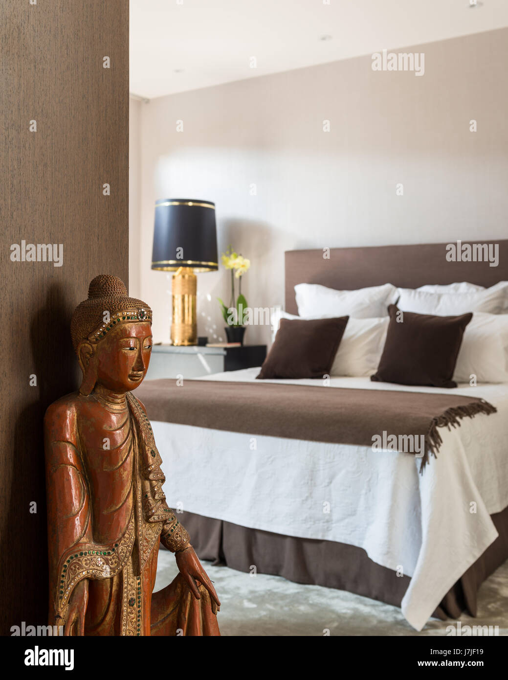 Bouddha en bois sculpté doré dans la chambre avec lampe de chevet Photo  Stock - Alamy