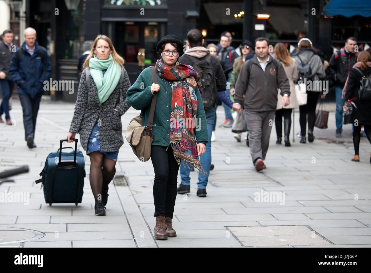 Londres, ANGLETERRE - 12 mars 2017 une femme dans un black hat et gaine verte promenades dans la foule parmi les autres passant Banque D'Images