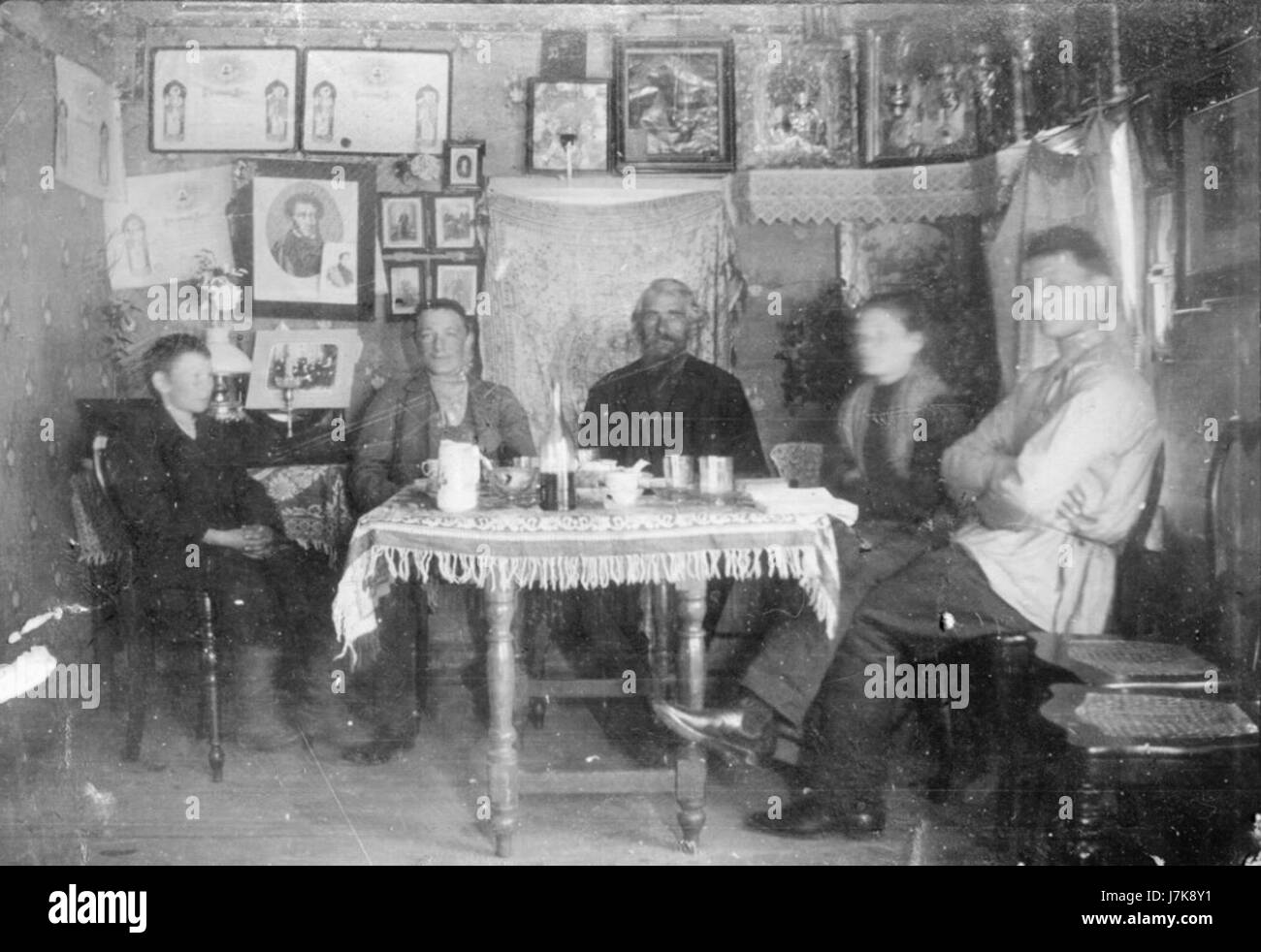 Cette image montre un groupe de personnes rassemblées autour d'une table à la maison, probablement engagées dans une activité commune comme un repas ou une conversation. Il reflète les interactions familiales ou sociales dans un contexte domestique. Banque D'Images