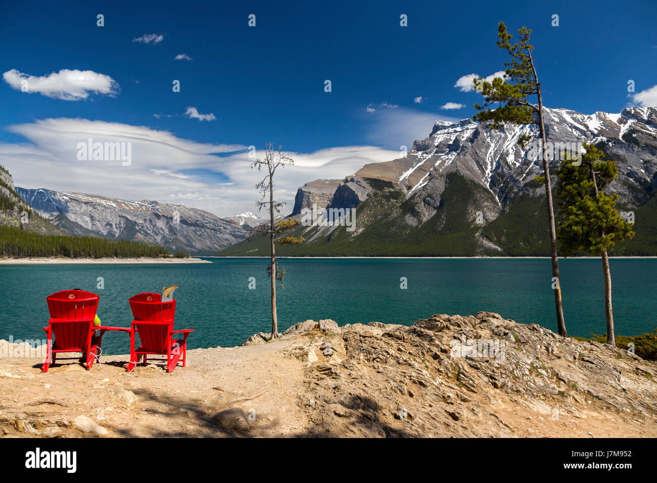 Chaises Red Adirondack Blue Lake Minnewanka Skyline des montagnes Rocheuses canadiennes.Vue panoramique sur le parc national de Banff Paysage Clear Springtime Day View Banque D'Images