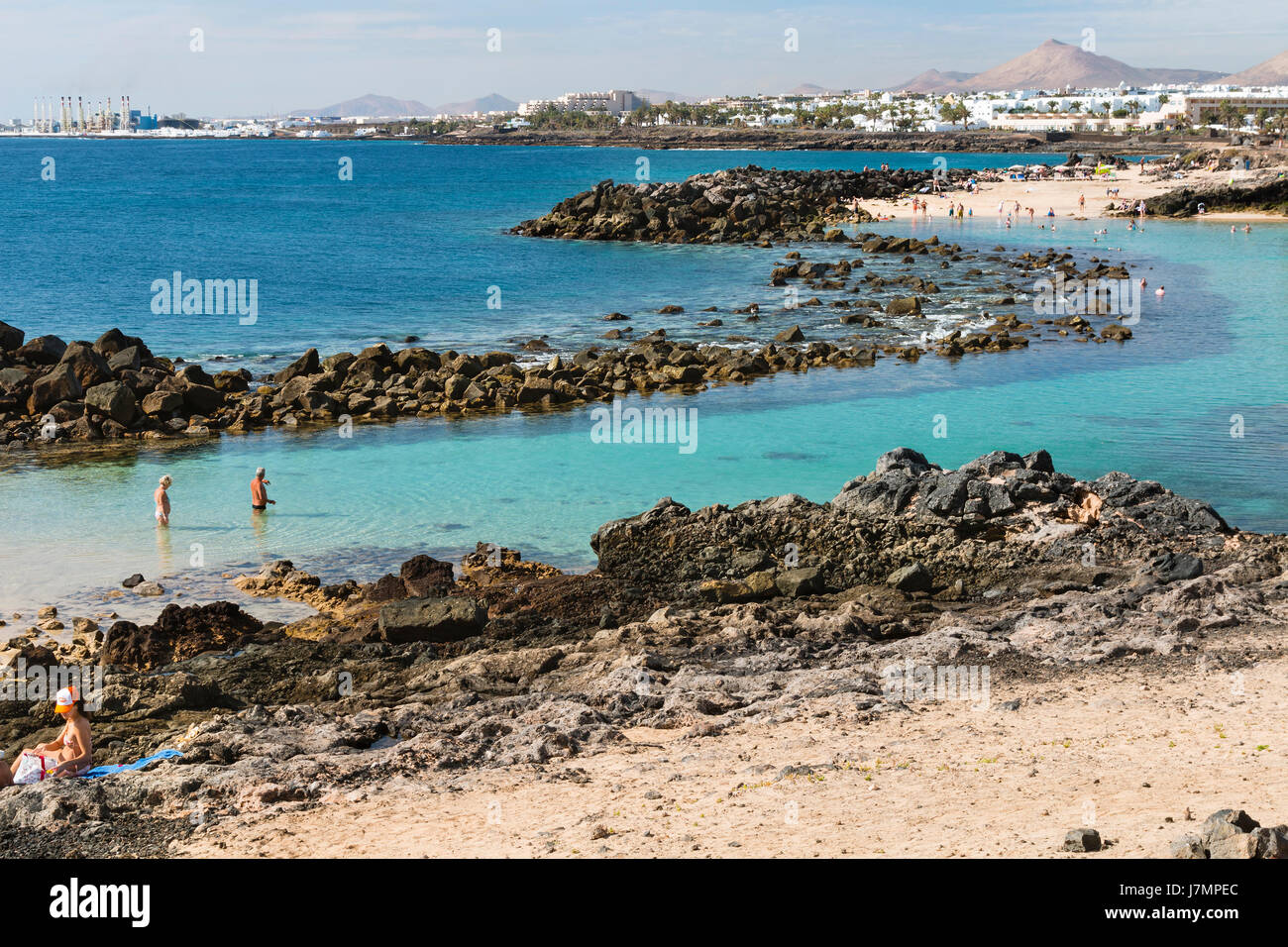 LANZAROTE - 14 janvier : personnes à un lagon à la plage de Costa Teguise à Lanzarote, Espagne avec le village en arrière-plan le 14 janvier 2016. Banque D'Images