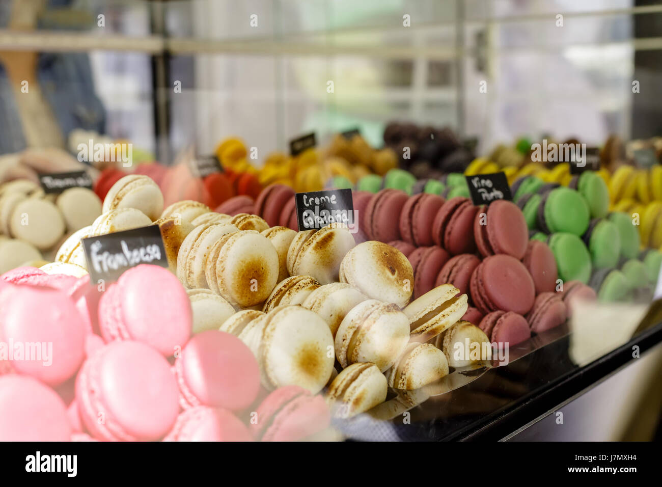 Des petits macarons assortiment à la vente avec un signe en disant : framboise, crème catalane et diverses saveurs Banque D'Images