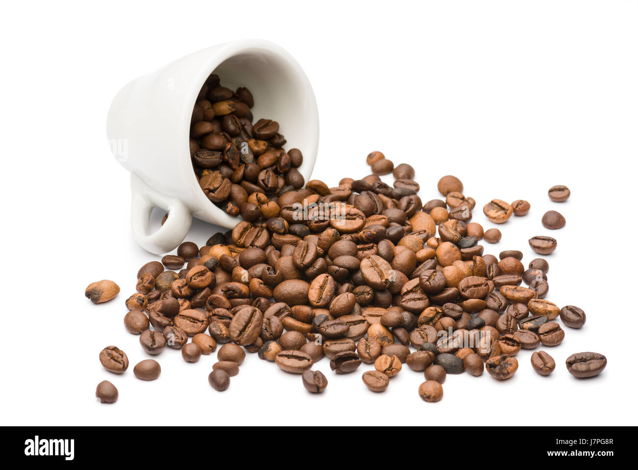 La tasse de café renversée avec des tas de grains de café, sur fond blanc Banque D'Images