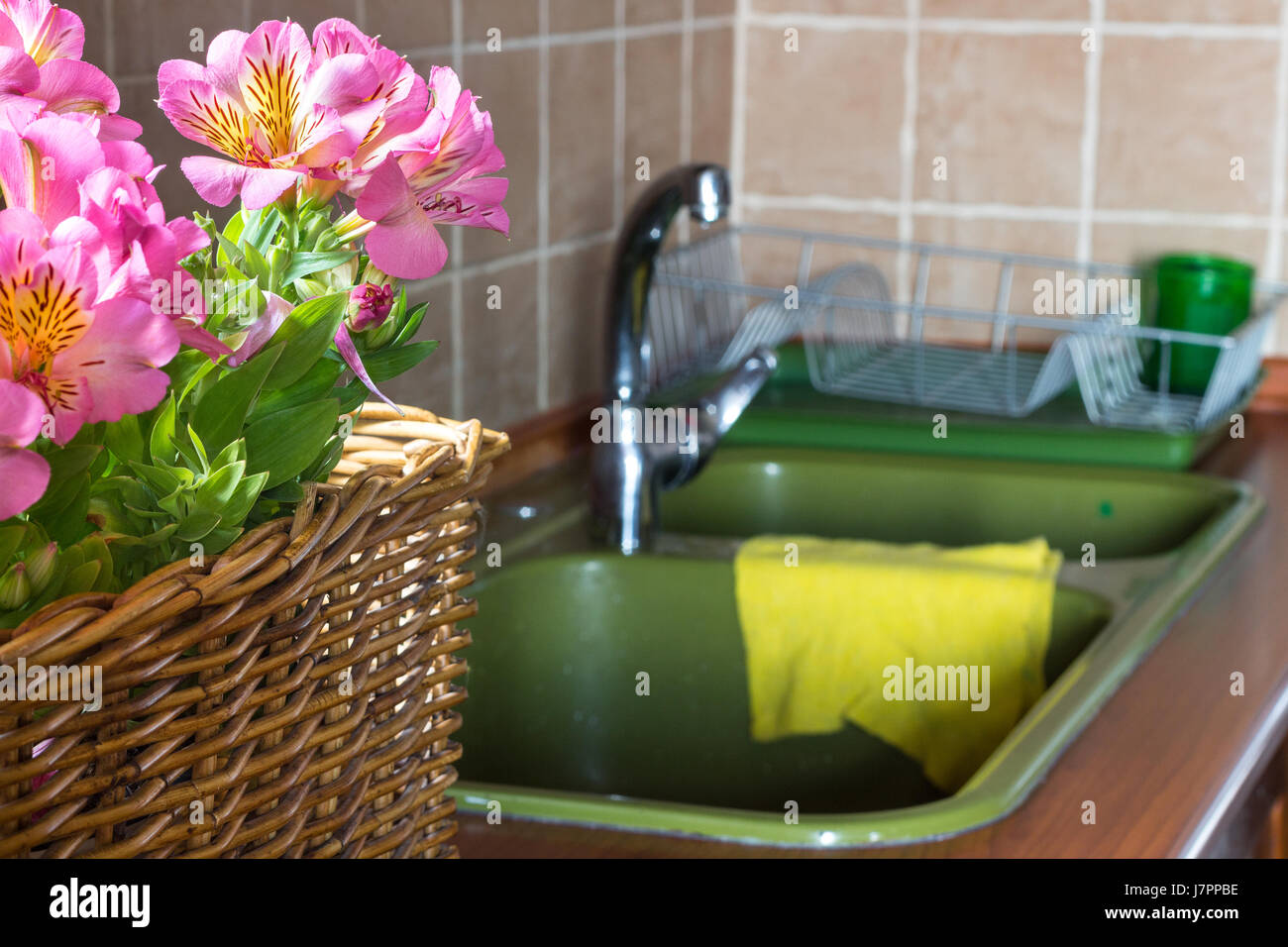 Un panier de fleurs sur une table avec un évier et un robinet. Banque D'Images