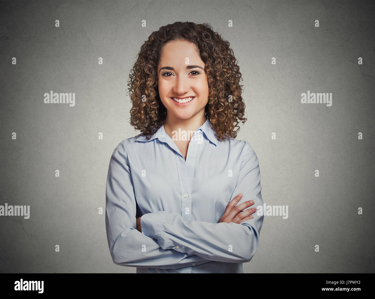 Closeup portrait, heureux, confiant, le succès de jeune professionnel femme en chemise bleue avec les bras croisés isolé mur gris plié. Positif Banque D'Images