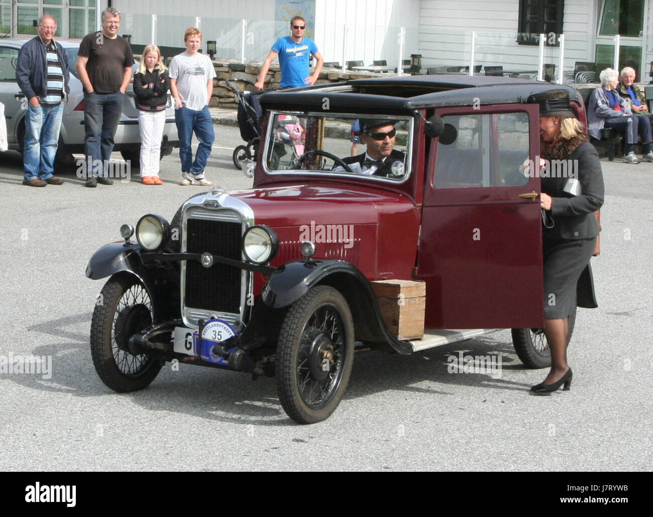 Une voiture Singer Junior Saloon 8 HP de 1931, appartenant à Kjartan Meyer, représentée en tenue d'époque aux côtés d'une dame de compagnie dans un style similaire, mettant en valeur la culture automobile et la mode du début du XXe siècle. Banque D'Images