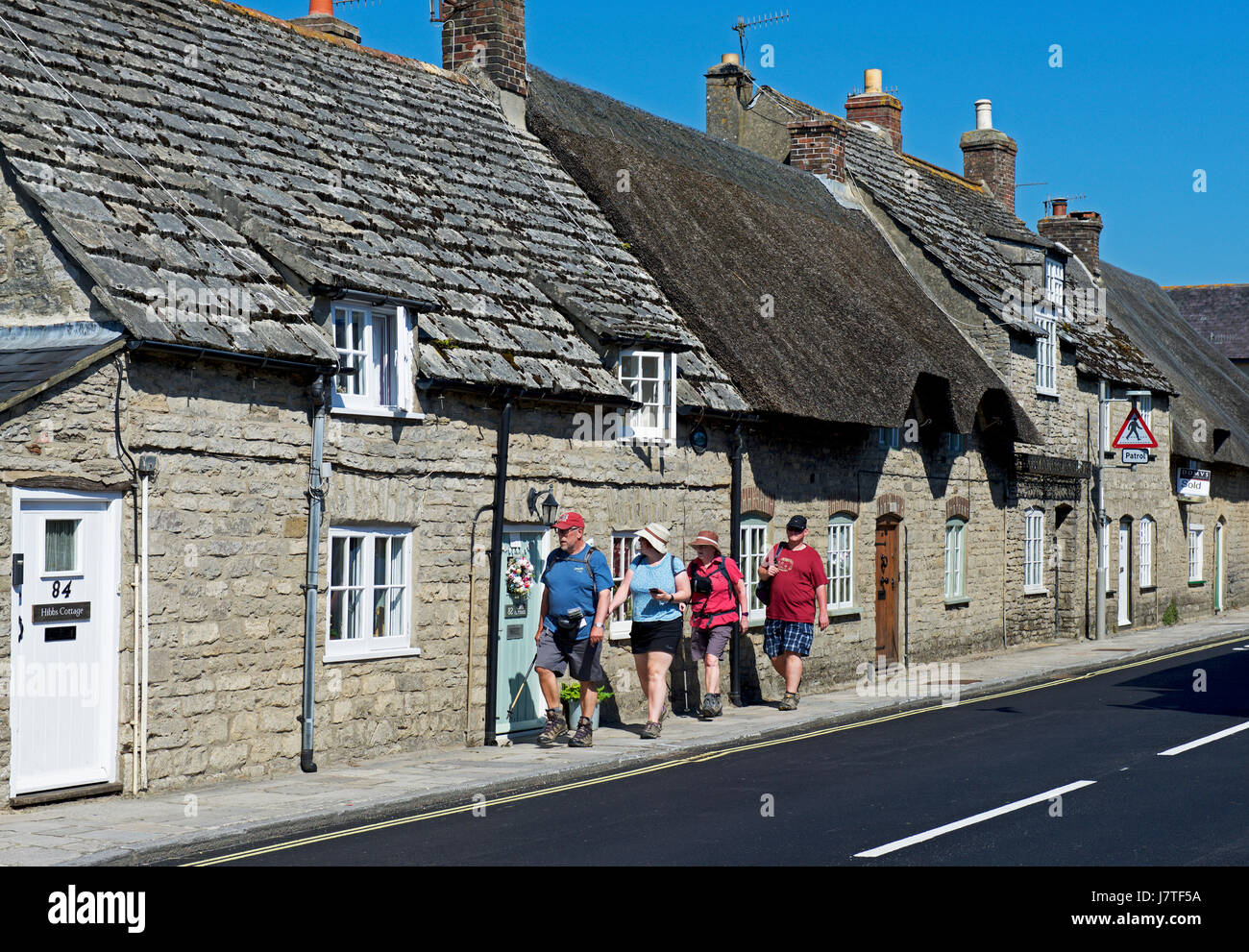 Quatre personnes à pied à travers le village de Corfe Castle, Dorset, England UK Banque D'Images