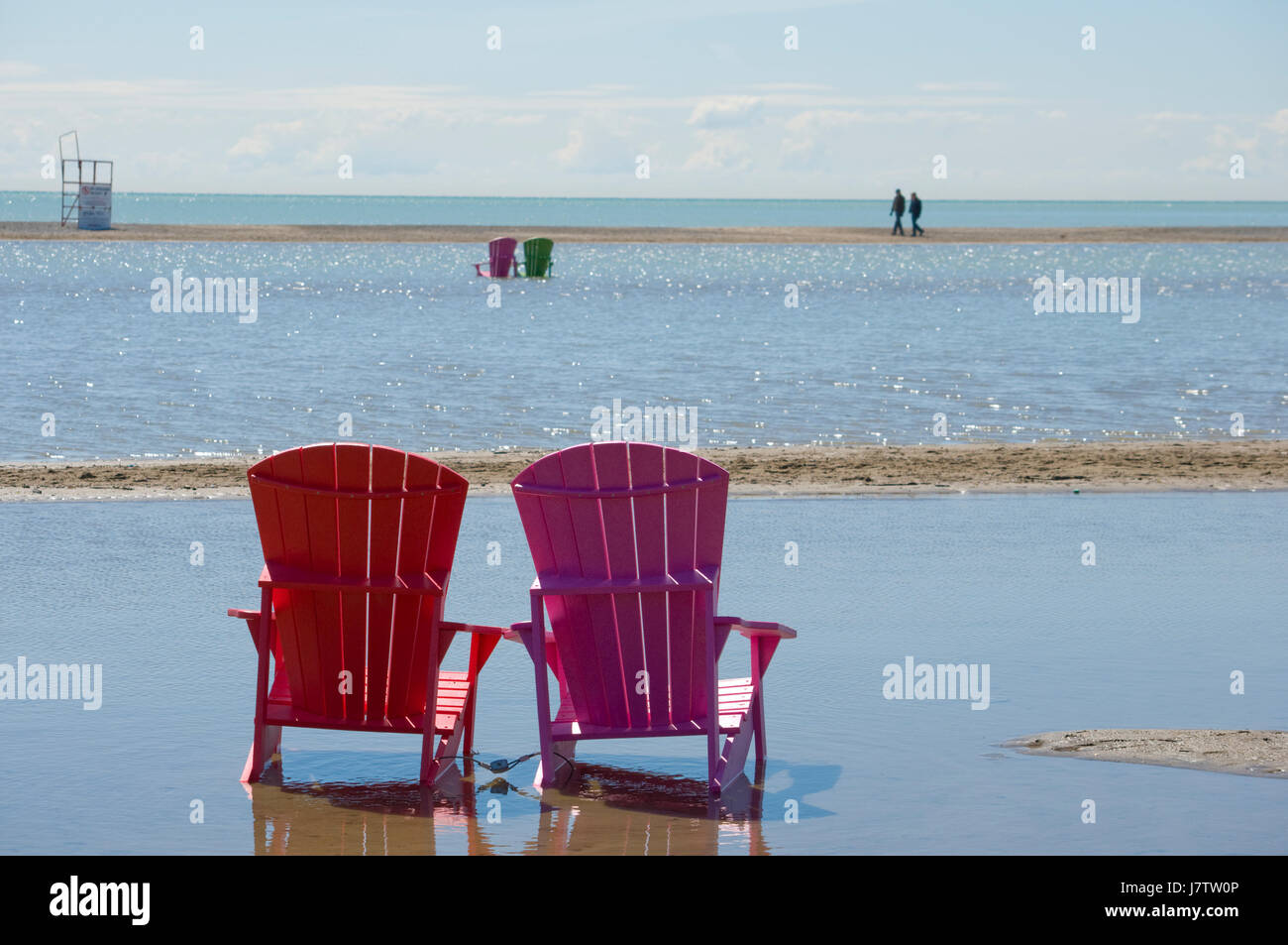 Chaises Muskoka partiellement immergé dans l'eau et le sable après les inondations printanières et des eaux du lac à Toronto, Ontario, Canada Banque D'Images