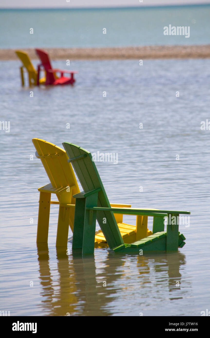 Chaises Muskoka partiellement immergé dans l'eau et le sable après les inondations printanières et des eaux du lac à Toronto, Ontario, Canada Banque D'Images