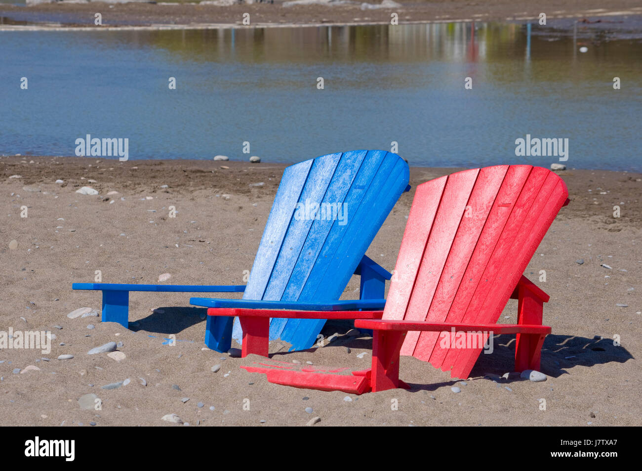 Chaises Muskoka partiellement immergé dans l'eau et le sable après les inondations printanières et des eaux du lac à Toronto, Ontario, Canada Banque D'Images